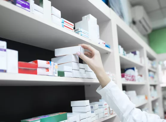 Closeup view of pharmacist hand taking medicine box from the shelf in drug store