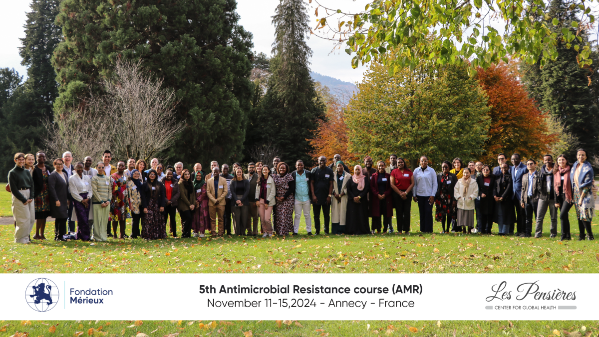 Attendees of the 5th AMR course outside in a wooded area. Caption reads "5th Antimicrobial resistance course (AMR), November 11-15, 2024 - Annecy - France, with logos of the Merieux foundation and les pensieres.