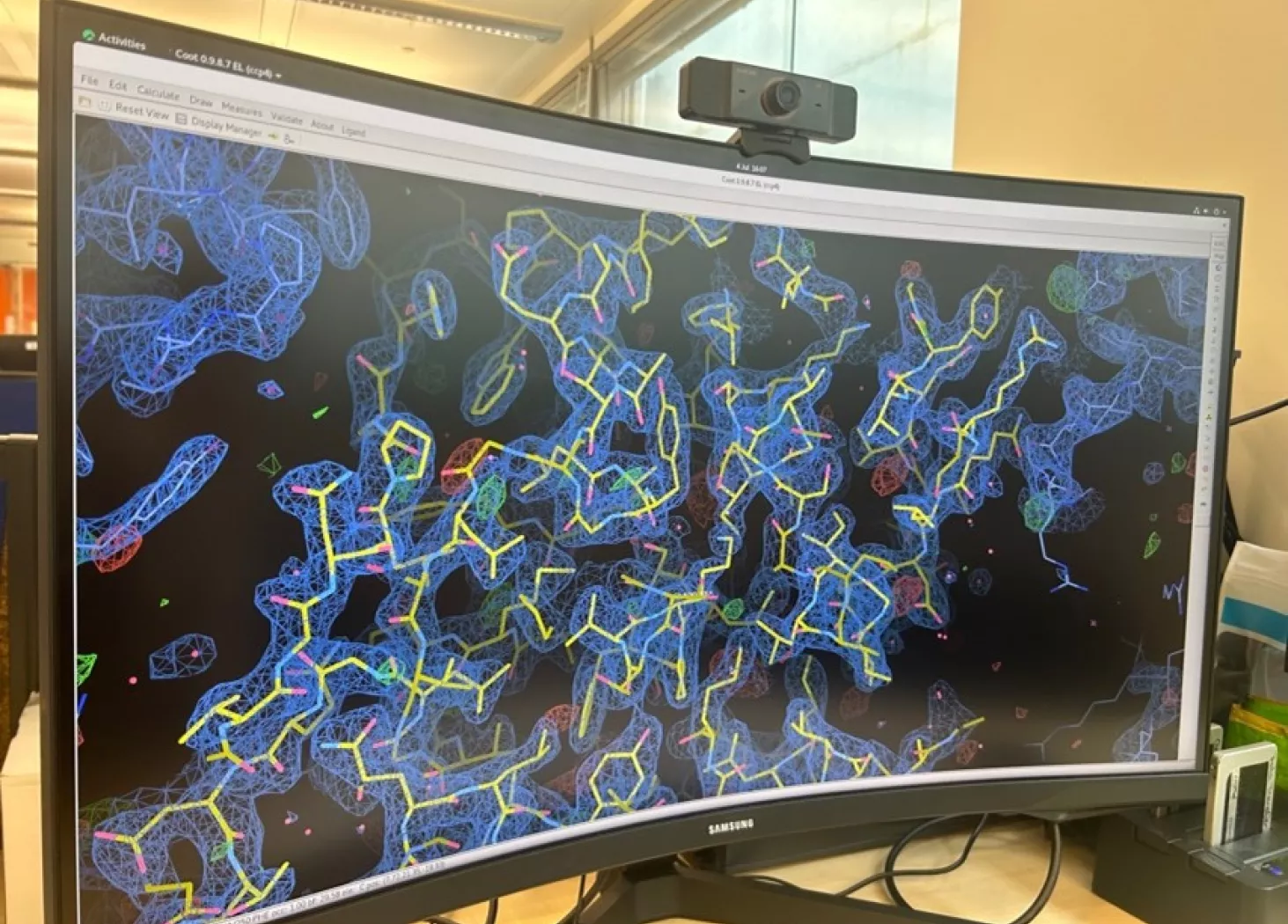 Computer screen showing a 3D model of protein structure, in bright blue and yellow 